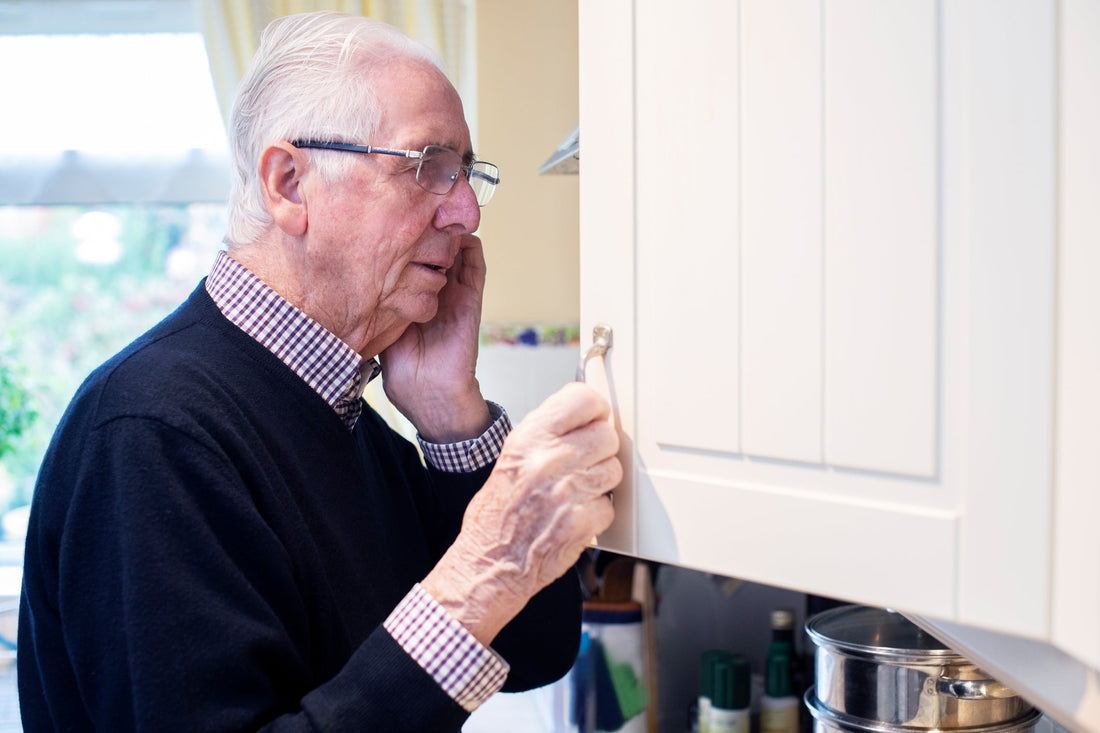 Older man searching a kitchen cupboard for a misplaced hearing aid