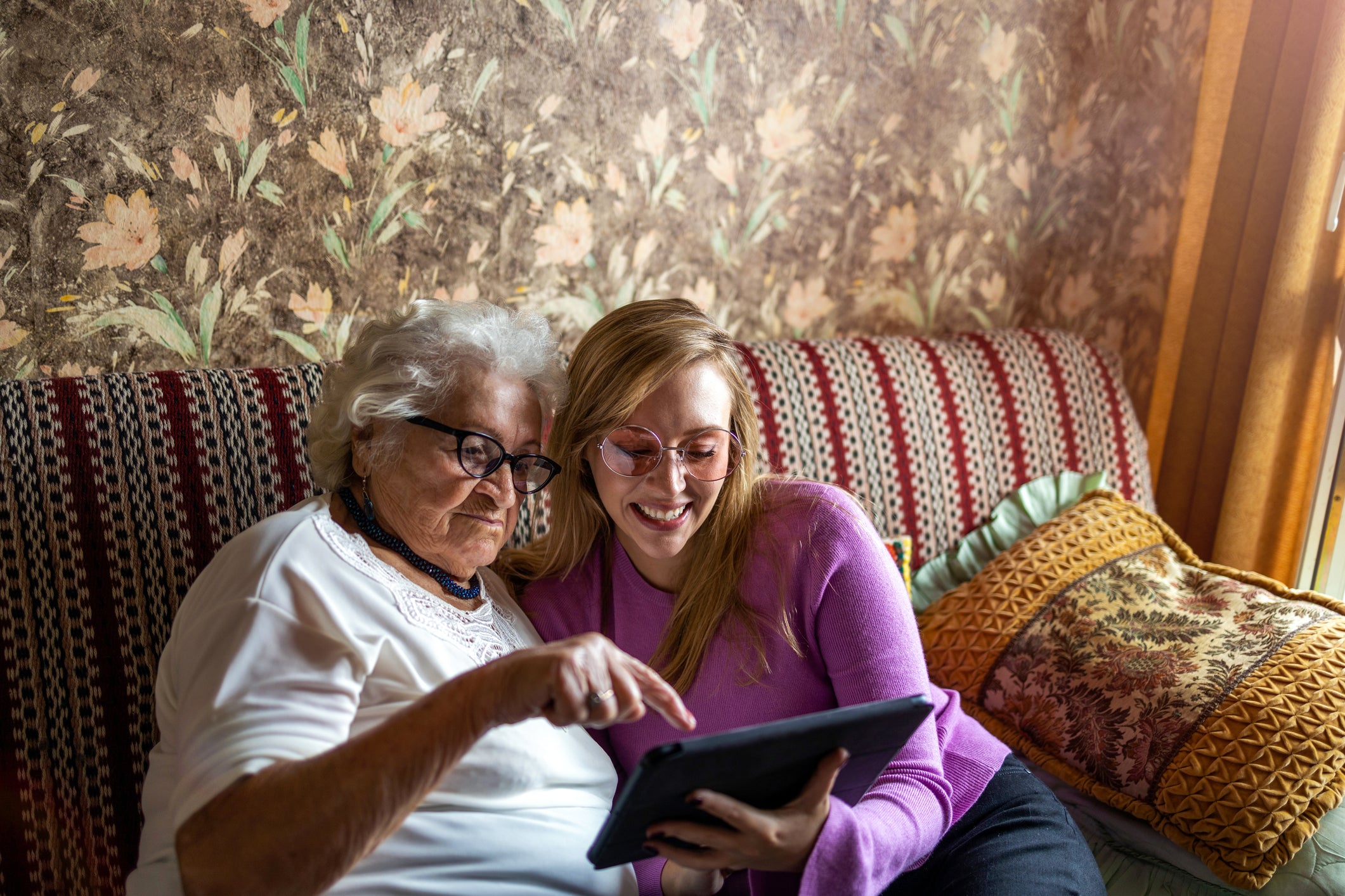 Older adult and family member looking at a tablet together